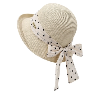Elegant ivory sun hat with wide brim, dotted ribbon bow, and gold metal charm