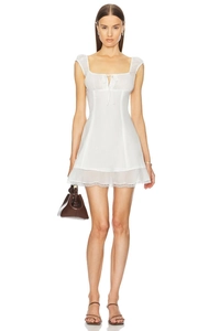 White sleeveless lace mini dress with bow-tie waist and sheer details on a model