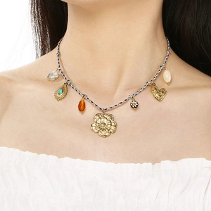 Detail of colorful woven rope necklace with gold flower, heart and bead charms on model