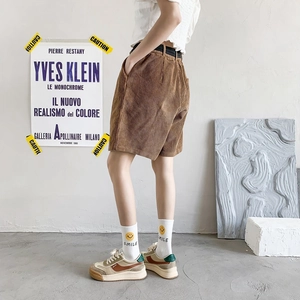 Detail view of brown corduroy shorts in a retro style worn by a fashion model