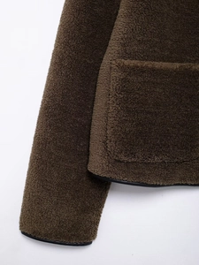 Close-up of brown fleece jacket showing plush texture and black leather piping detail