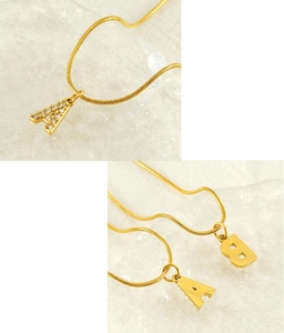 Detail of gold stainless steel A and B letter pendants with zircon on a snake chain