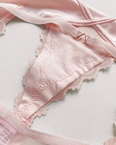 Detail of pink silk thong featuring lace edges and a heart-shaped metal adjustment buckle