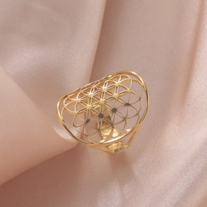 Elegant gold hollow flower ring with geometric patterns on soft pink satin fabric