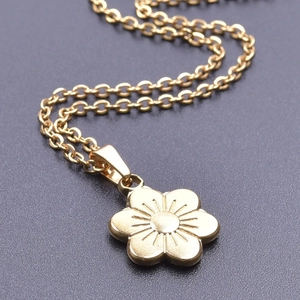 Close-up of gold-plated flower pendant with radial engraving and polished 18k finish