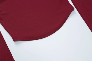 Dettaglio top in maglia a coste bordeaux con orlo curvo e cuciture a doppio ago