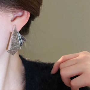 Close-up of stylish irregular geometric silver metal stud earrings worn by a model
