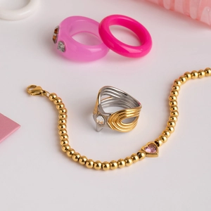 Détail d'une bague étoile en titane et bracelet perlé avec cœur rose brillant