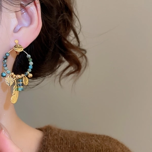 Detailed close-up of a vintage feather pendant clip-on earring worn on the ear