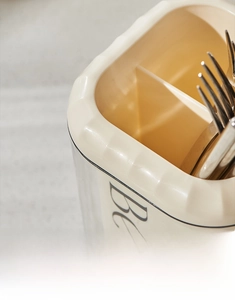 Detail of cream cutlery holder featuring rounded edges and internal dividers for spoons