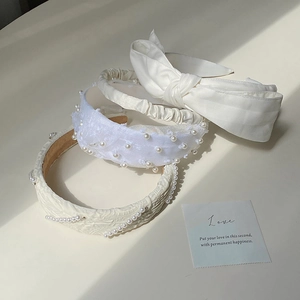 Detail showing white pearl headbands with bow and lace textures on a beige background