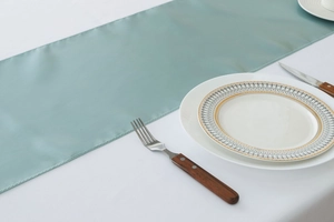 Detail shot of light blue satin table runner texture on a clean white tablecloth