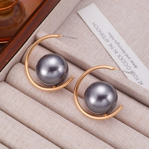 Macro shot of dark grey large pearls on C-shaped gold metal hoop earrings for women