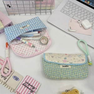 Detailed view of quilted cotton pencil cases with floral patterns on a white desk