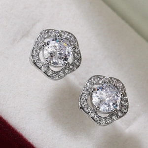 Macro shot of silver flower earrings with zircon stones on a soft jewelry box lining