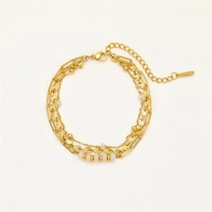 Three-layer gold stainless steel bracelet with white beads and etched charms on white background