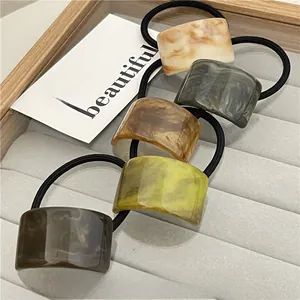 Detailed macro view of 5 marbled resin hair ties on a grey velvet jewelry tray stand