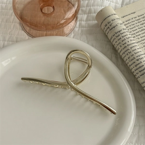 Detailed view of a golden metal hair claw clip placed on a white ceramic plate