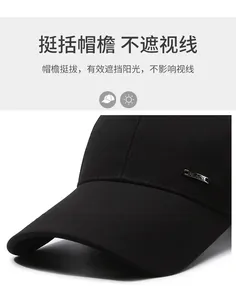 Detail of a black baseball cap featuring an long curved brim and silver metal logo plaque