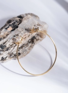 Detailed close-up of a gold open cuff bracelet with square zircon on mineral stone