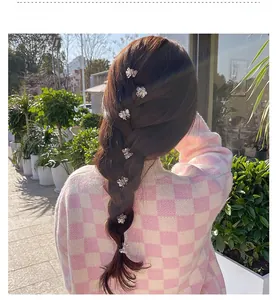 Detailed view of mini camellia flower hair clips with pearls styled on a braid