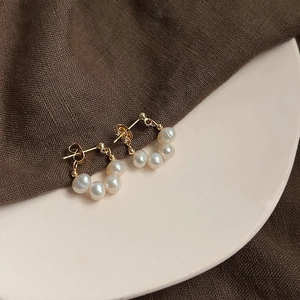 Close-up of baroque pearl earrings with five white pearls in gold setting on a tray