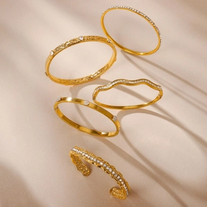 Vista macro di cinque bracciali dorati con zirconi bianchi incastonati e texture martellate