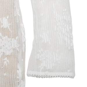 Vue détaillée de la manche en dentelle blanche avec motif ajouré et bord festonné