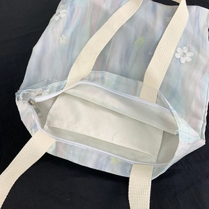Détail de la poche intérieure zippée et broderie florale sur le sac cabas bleu