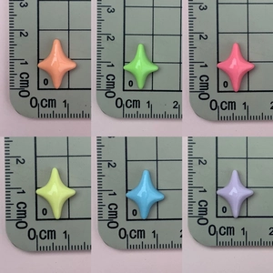 Detailed view of colorful resin star charms on a ruler grid for size reference