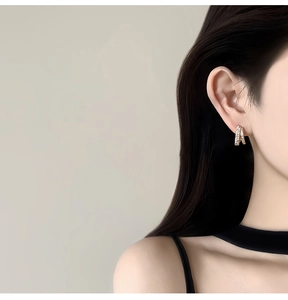 Close-up of 14k gold plated stud earrings with pavé zircons worn by a model