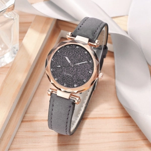 Detail of rose gold watch with starry grey dial and leather strap on a textured wood surface