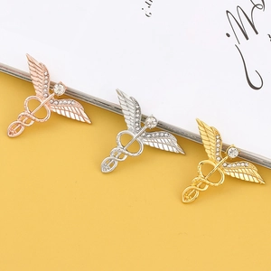 Detailansicht der Caduceus-Broschen in Gold, Silber und Roségold mit funkelnden Kristallen