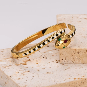 Golden snake bracelet with green stone eyes and black and white enamel on beige stone base