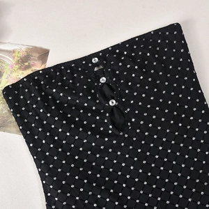 Détail d'un haut bustier noir avec pois argentés et boucles ornées de strass brillants
