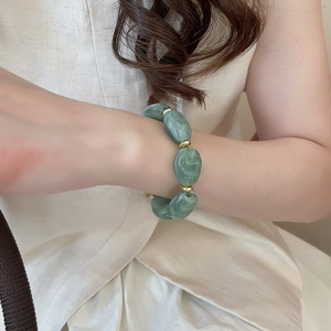 Detailed shot of olive green acrylic oval beads and golden metal spacers on wrist