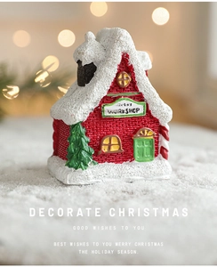 Détail d'une maison de Noël en résine avec toit enneigé et texture de brique rouge