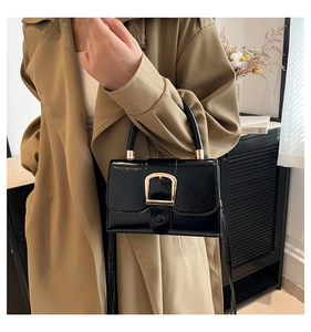 Dettaglio dell'elegante mini borsa nera lucida con fibbia a D dorata e manico corto