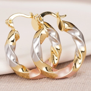 Three-tone twisted hoop earrings in gold, silver, and rose gold with a polished finish