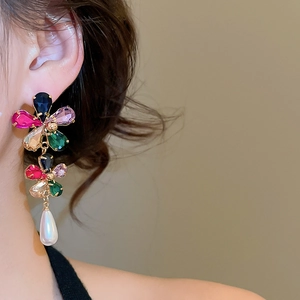Close-up of dangling flower earrings with multicolor rhinestones and pearl drop