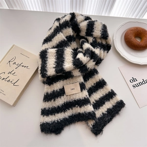 Close-up of soft black and white striped knit scarf with plush wool texture and ins label