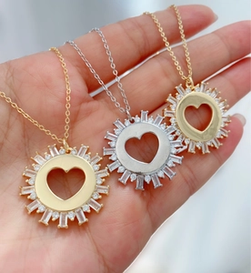 Detailed view of three sunburst heart pendants with zircon stones in gold and silver finish