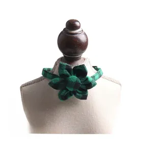 Detail view of British style green plaid pet collar with decorative bow on a white background