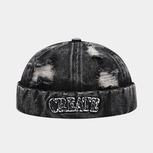 Detail of washed black denim docker hat with CREATE embroidery and distressed holes