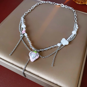 Detail einer zweischichtigen Kette mit rosa Herzanhänger und Perlen auf einer Box