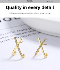 Detail of 925 sterling silver X-shaped earrings with gold plating and cubic zirconia