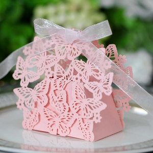 Detail of pink laser-cut butterfly candy box with white organza ribbon bow on a plate