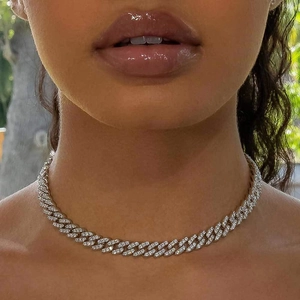 Close-up of silver Cuban link necklace with pavé set diamonds on model neck