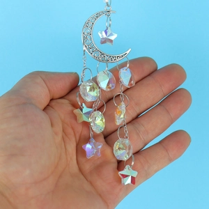 Macro detail of silver moon suncatcher with clear crystal stars held against a blue sky
