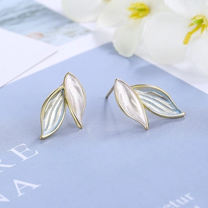 Macro shot of gold-rimmed blue and white gradient leaf earrings with enamel finish